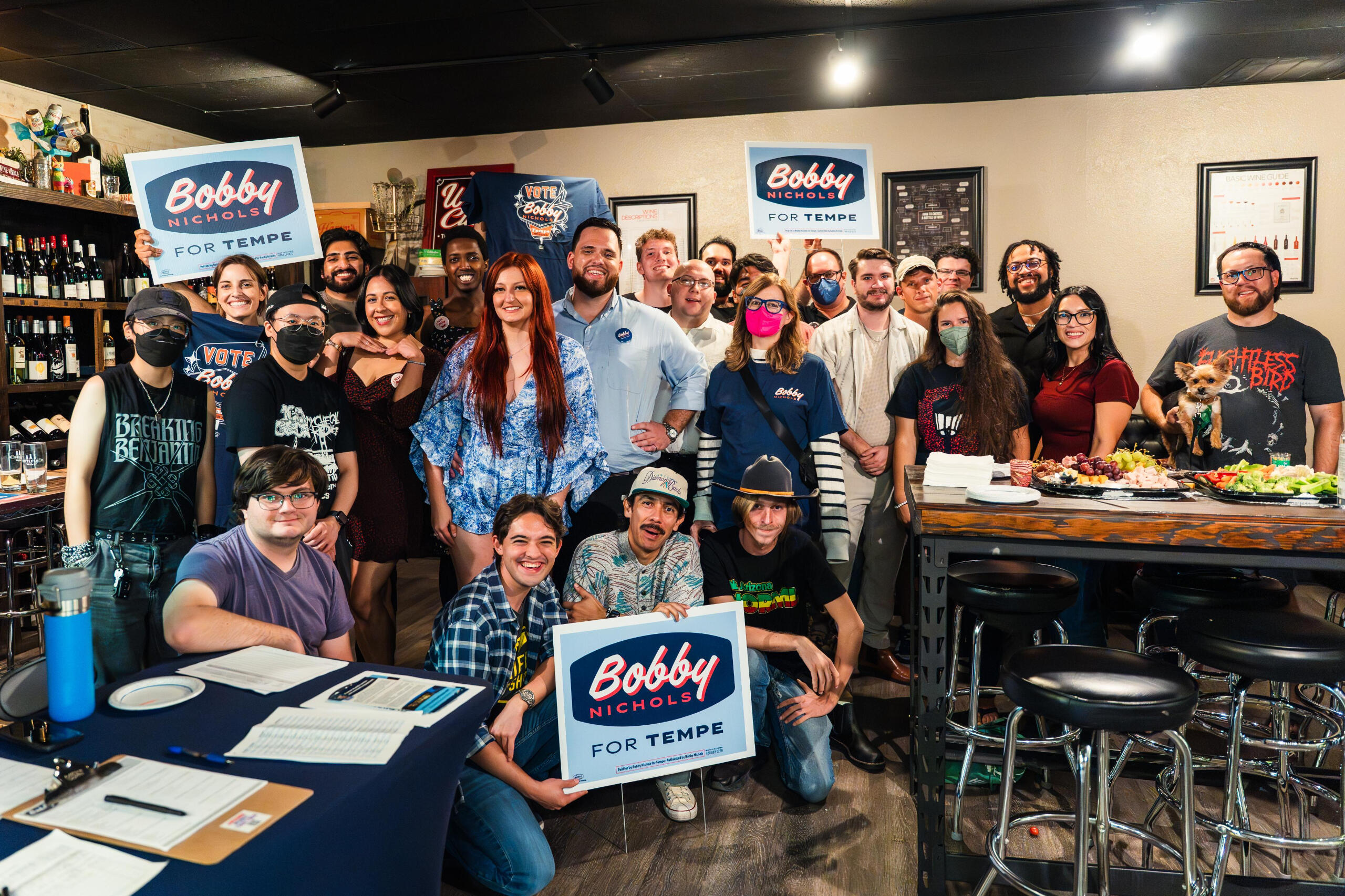 Group of campaign volunteers and supporters indoors holding Bobby Nichols for Tempe signs and smiling at the camera.
